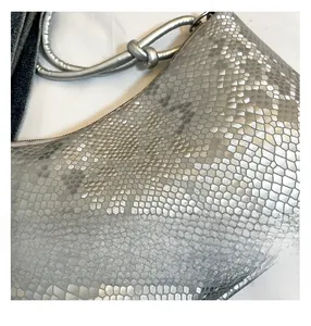 Detail of silver snakeskin texture handbag with metallic finish and knotted handle detail
