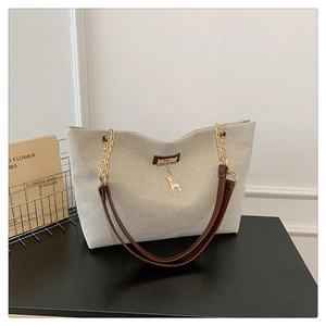 Détails du sac fourre-tout en toile beige avec anses marron et pendentif cerf doré