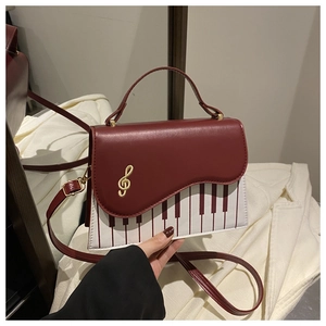 Detail of piano keyboard design and golden music note embroidery on crossbody bag