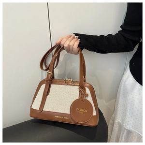 Detail of canvas tote bag with leather trim, zipper closure, and gold lettering