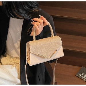 Detail of elegant gold crossbody bag with sparkling rhinestones and metal V-trim
