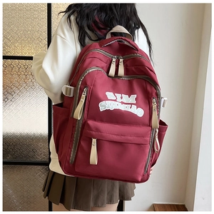 Detailed back view of a burgundy nylon backpack featuring white logo text and contrast straps