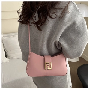 Detail of pink leather handbag with a gold geometric metal clasp and slim shoulder strap