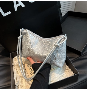Detailed view of silver snakeskin shoulder bag with thin straps and knotted accents