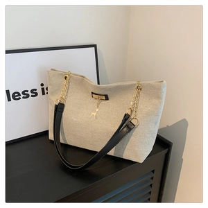 Détail du grand sac cabas beige tissé avec bandoulière cuir et pendentif doré
