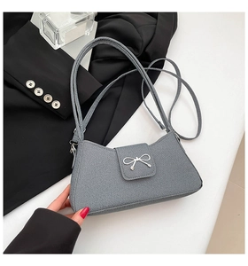 Close-up of greyish blue bow shoulder bag with silver metallic hardware and rib texture