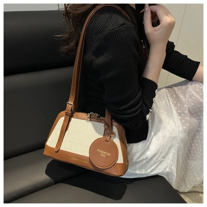 Detailed side view of canvas and leather tote bag with elegant hanging brand tag