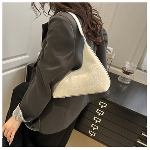 Detailed side view of white triangular underarm bag with snake texture and metal studs