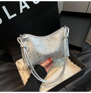 Detail of silver snake-pattern shoulder bag with metallic texture in gift packaging