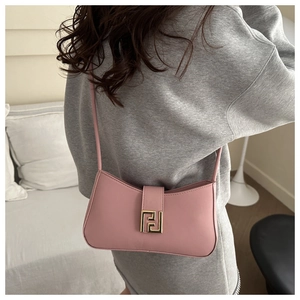 Rear view of model wearing a pink leather baguette bag with gold buckle on casual grey outfit