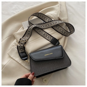 Detail of minimalist leather crossbody bag with ethnic style jacquard wide strap