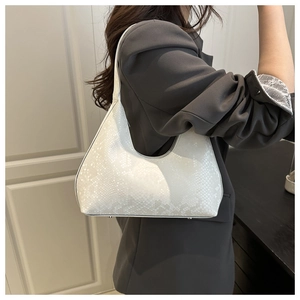 Detailed side view of white faux snakeskin hobo bag worn by a model in a grey suit