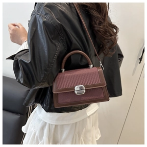 Détail d'un petit sac bandoulière en cuir marron et tissé rose avec fermoir argenté