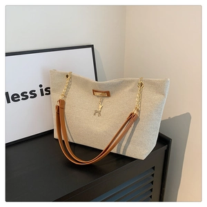 Détail du grand sac cabas beige avec lanières brunes, chaîne et pendentif cerf