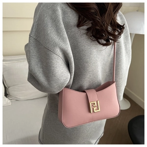 Close-up of pink crescent underarm bag with iconic gold metal buckle and leather texture