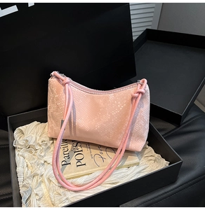 Detail shot of a pink snakeskin embossed shoulder bag on white fabric in a box