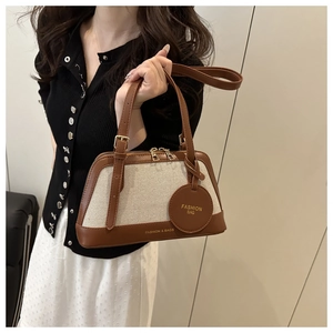 Detailed close-up of canvas tote bag with brown leather trim and fashion tag detail