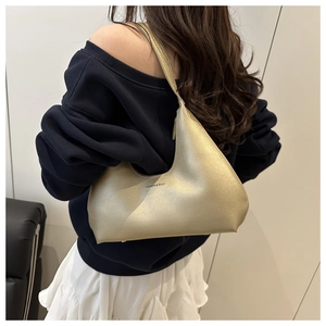 Detail of champagne gold metallic hobo bag showing glossy texture and fashion logo