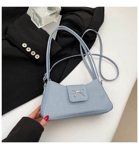 Detail of light blue denim fabric handbag with silver bow buckle and twill texture