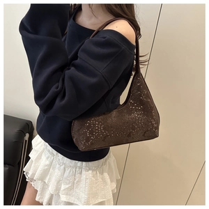 Close-up of brown snakeskin texture on a retro half-moon shoulder bag worn by model