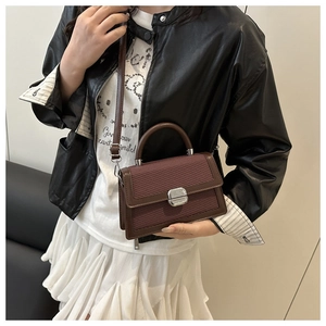 Vue détaillée d'un sac bandoulière marron tissé avec boucle argentée porté par un modèle