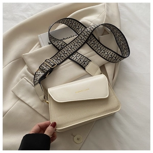 Detail of beige flap bag featuring woven texture and geometric pattern wide strap