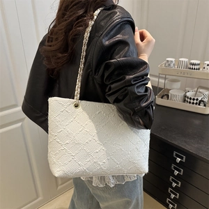 Sac fourre-tout blanc en tweed avec bandoulière chaîne porté par un mannequin chic