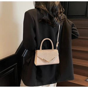 Detail of light beige crossbody bag with rhinestone handle and golden V-shaped trim