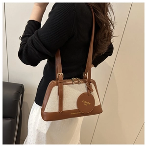 Detail of canvas and brown leather tote bag worn as an underarm shoulder bag