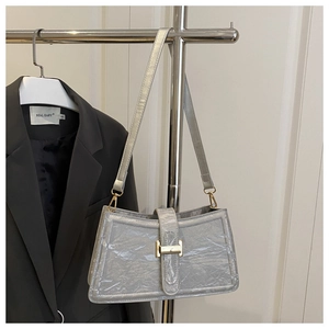 Close-up of wrinkled silver bag with metallic finish and gold-toned H-shaped clasp
