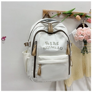 Close-up of a white nylon backpack featuring multiple zipper pockets and side straps