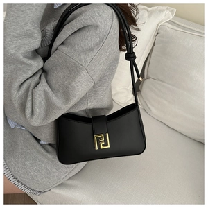 Close-up of black matte leather shoulder bag featuring a luxury gold geometric buckle