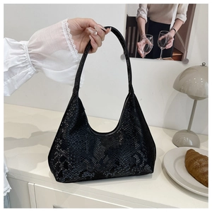Detail of black faux snake texture on a minimalist crescent-shaped shoulder bag