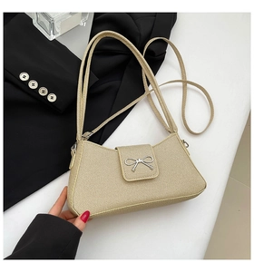 Close-up of beige woven texture handbag with silver metallic bow buckle detail