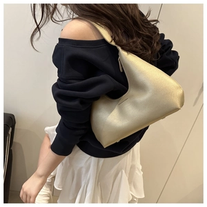 Detailed view of champagne gold hobo bag with a sleek matte finish on a female model