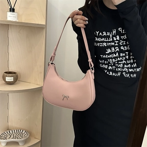 Close-up of pink half-moon hobo bag with a silver bow detail and matte leather finish