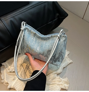 Detail view of light blue sequined shoulder bag with shimmering fabric and long straps