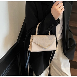 Fashionable sparkling crossbody bag with gold V-frame detail on elegant model