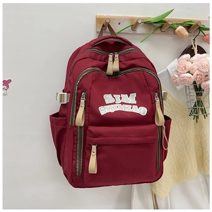 Close-up of a dark red nylon backpack featuring SJM SIJIMIAO lettering and beige ribbons