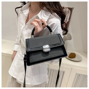 Détail de la texture en cuir tressé et boucle argentée d'un petit sac à main noir moderne