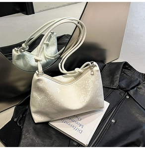 Detail of white faux leather underarm bag with snakeskin embossing and knot strap