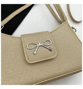 Close-up of beige woven texture bag featuring a silver metal bow buckle detail