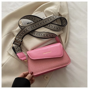 Detail of pink patchwork crossbody bag featuring woven texture and geometric strap