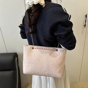 Sac fourre-tout matelassé rose avec bandoulière chaîne porté par un mannequin chic