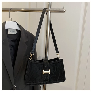 Detail of black baguette shoulder bag featuring pleated leather and a gold-tone metal lock