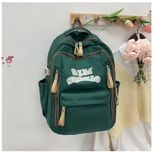 Detailed view of dark green nylon backpack showing zippers and durable strap buckles