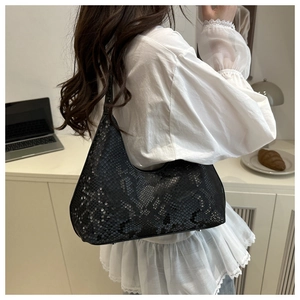 Detail of black faux leather half-moon bag with textured snakeskin pattern