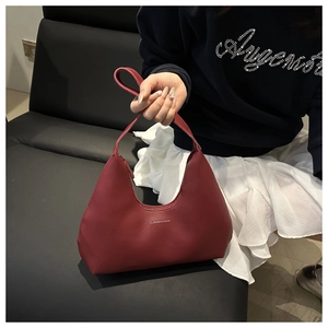 Close-up of wine red leather hobo bag with Fashion & Bags logo held by a model