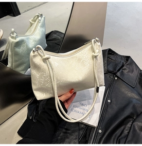 Detailed macro shot of white snakeskin texture and thick knotted straps on shoulder bag