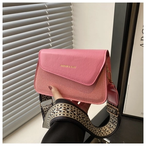 Detail of pink crossbody bag featuring woven texture and geometric patterned wide strap